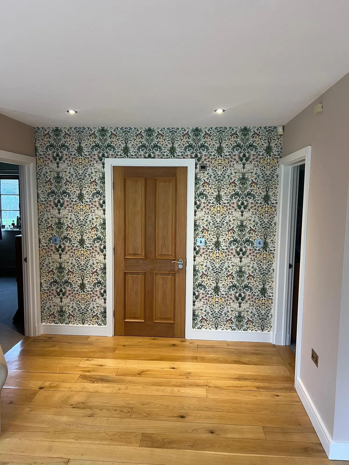 Hallway with patterned feature wallpaper around a wooden door